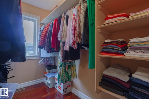 Walk-in closet featuring built-in shelving, hanging rods, wood-finish flooring, and a window - 10731 150 Street Nw, Edmonton, AB - Indoor With Storage