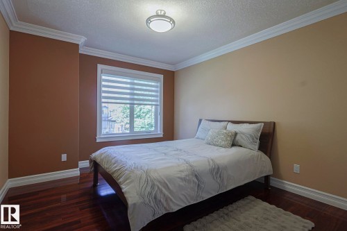 Bedroom featuring dark wood-finish flooring, two-tone wall paint, white crown molding, and a window with blinds - 10731 150 Street Nw, Edmonton, AB - Indoor Photo Showing Bedroom