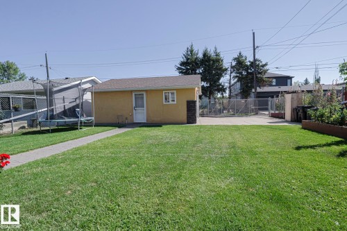 Expansive grassy yard area with a paved pathway leading to a detached structure - 10731 150 Street Nw, Edmonton, AB - Outdoor