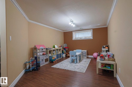 Spacious room featuring wood-finish flooring, a neutral wall color, and a contrasting accent wall - 10731 150 Street Nw, Edmonton, AB - Indoor Photo Showing Other Room