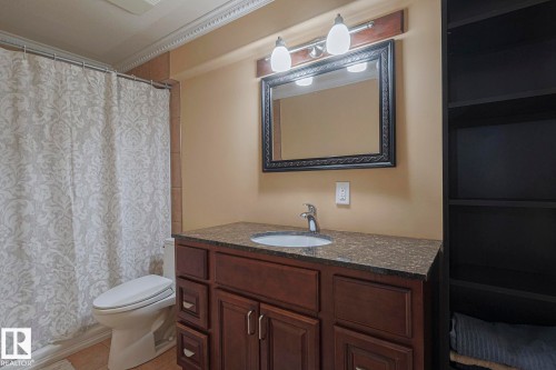 Bathroom featuring a wood-finish vanity with a granite-look countertop, undermount sink, and chrome faucet - 10731 150 Street Nw, Edmonton, AB - Indoor Photo Showing Bathroom