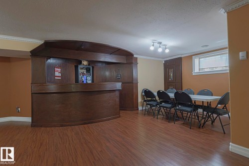 Spacious recreation room featuring wood-finish flooring and a built-in wooden bar - 10731 150 Street Nw, Edmonton, AB - Indoor