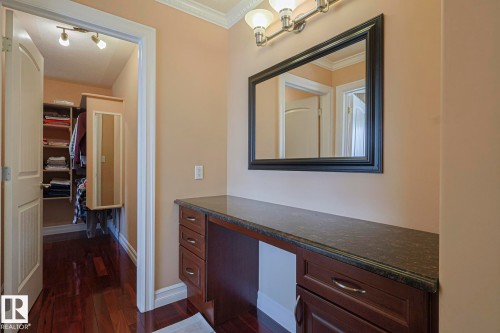 Vanity area featuring dark wood-finish cabinetry, a dark stone-finish countertop, and a framed mirror with overhead lighting - 10731 150 Street Nw, Edmonton, AB - Indoor Photo Showing Other Room