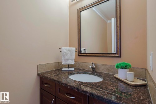 Vanity featuring a dark wood finish cabinet, integrated sink, and granite countertop - 10731 150 Street Nw, Edmonton, AB - Indoor Photo Showing Bathroom