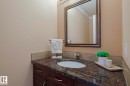 Vanity featuring a dark wood finish cabinet, integrated sink, and granite countertop - 10731 150 Street Nw, Edmonton, AB  - Indoor Photo Showing Bathroom 