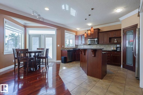 Kitchen featuring dark wood cabinetry, a central island with countertop, and stainless steel appliances - 10731 150 Street Nw, Edmonton, AB - Indoor
