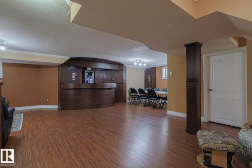 Spacious finished lower level featuring wood-finish flooring, a built-in wooden bar, recessed lighting, and crown molding - 10731 150 Street Nw, Edmonton, AB - Indoor