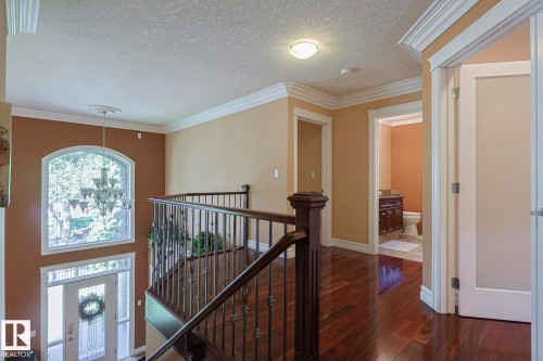 Two-story foyer with an arched window, a chandelier, and a wood-finish staircase featuring decorative metal balusters - 10731 150 Street Nw, Edmonton, AB - Indoor Photo Showing Other Room