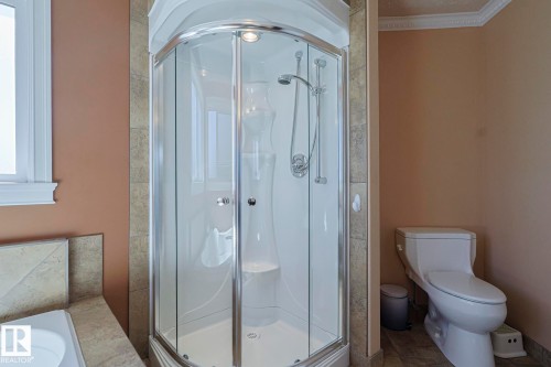 Corner glass shower enclosure with integrated lighting, a handheld showerhead, and a built-in seat - 10731 150 Street Nw, Edmonton, AB - Indoor Photo Showing Bathroom