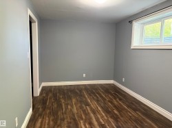 Room featuring wood-finish flooring, light gray walls, white baseboards, and a white-framed window - 