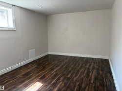 Spacious room featuring wood-finish flooring, light neutral wall paint, and white baseboards - 