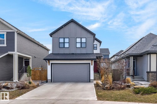 Modern farmhouse exterior featuring vertical siding, black-framed windows, an attached two-car garage, and a concrete driveway - 1091 Secord Promenade, Edmonton, AB 