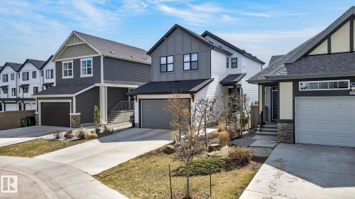 Modern residential exterior featuring a light gray garage door, stone accents, and dark trim details - 1091 Secord Promenade, Edmonton, AB 