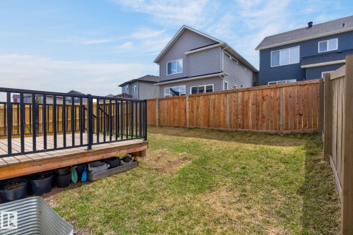 Expansive backyard featuring a wood deck with black metal railings, a wood privacy fence, and a green lawn - 1091 Secord Promenade, Edmonton, AB 