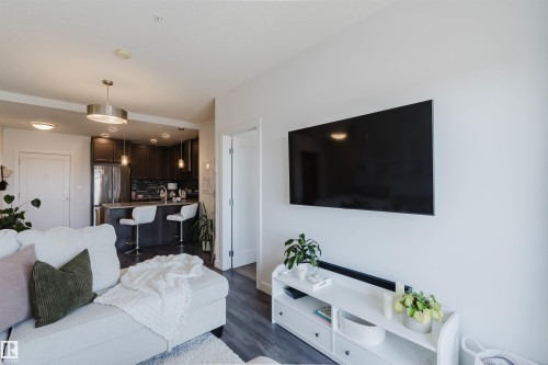 Open-concept living space featuring wood-finish flooring, recessed lighting, and a modern kitchen with dark cabinetry and stainless steel appliances - 316 1316 Windermere Way, Edmonton, AB - Indoor Photo Showing Living Room