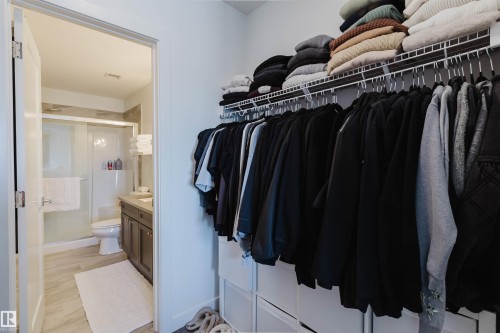 Integrated closet storage system with hanging rods and upper shelving - 316 1316 Windermere Way, Edmonton, AB - Indoor With Storage