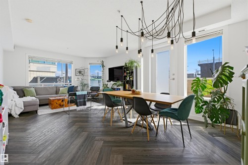Open-concept living area featuring a wood-finish herringbone pattern floor, high ceilings, and recessed lighting - 101 8108 109 Street, Edmonton, AB - Indoor