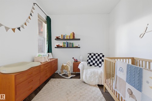 Bright room featuring white walls, a single window with dark green drapes, and dark wood-finish flooring - 101 8108 109 Street, Edmonton, AB - Indoor