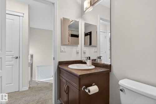Bathroom vanity featuring a white oval sink, dark wood-finish cabinetry, a coordinating countertop, and a large wall-mounted mirror - 21722 99A Avenue Nw, Edmonton, AB - Indoor Photo Showing Bathroom