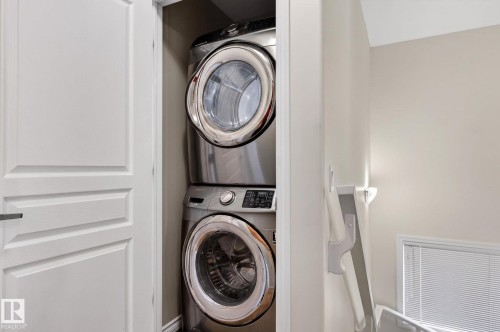 Dedicated laundry closet featuring a stacked washer and dryer, paneled bi-fold doors, and neutral wall paint - 21722 99A Avenue Nw, Edmonton, AB - Indoor Photo Showing Laundry Room