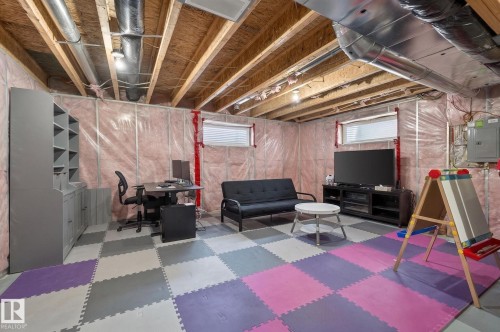 Unfinished basement space featuring exposed wood joists and ductwork, multiple windows, and a built-in storage cabinet - 21722 99A Avenue Nw, Edmonton, AB - Indoor Photo Showing Basement