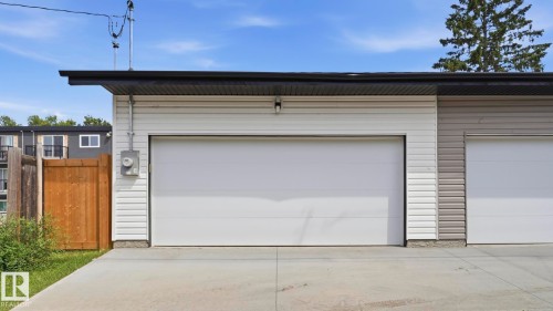 Concrete driveway leading to a two-door garage with white panel doors and horizontal siding - 11036 128 Street Nw, Edmonton, AB - Outdoor With Exterior