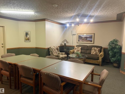 This space features a dining area with multiple tables and chairs, alongside a lounge area with a sofa and armchair - 101 9760 174 Street, Edmonton, AB - Indoor Photo Showing Other Room