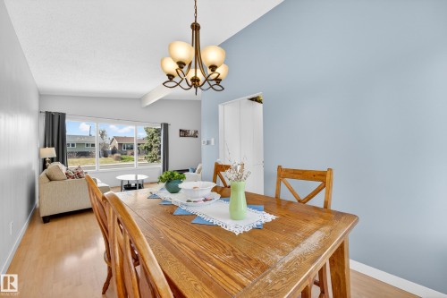 Dining area featuring a wood-finish table, overhead chandelier, and wood-finish flooring - 5304 90A Avenue, Edmonton, AB 