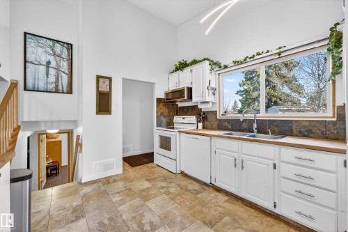 Kitchen featuring white cabinetry, wood-finish countertops, and a tile backsplash - 5304 90A Avenue, Edmonton, AB 