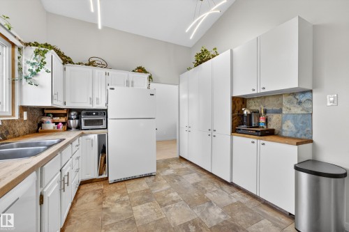 Kitchen area featuring white cabinetry, wood-finish countertops, and a double basin stainless steel sink - 5304 90A Avenue, Edmonton, AB 