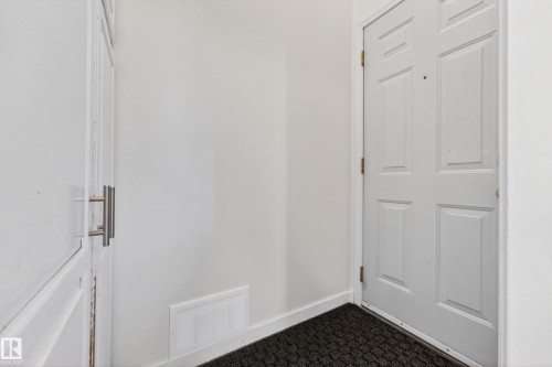 White paneled door with brass-toned hardware, featuring a black textured mat at its base - 5304 90A Avenue, Edmonton, AB 