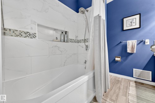 Bathtub and shower surround featuring large format marble-look tile with decorative mosaic accent - 5304 90A Avenue, Edmonton, AB 