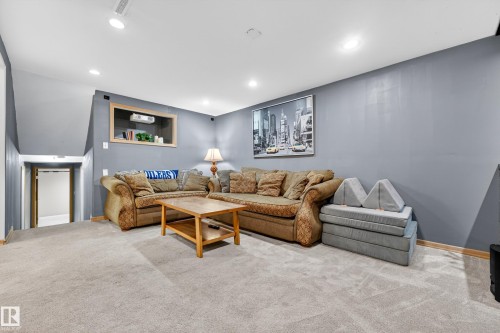 Carpeted lower-level room featuring recessed lighting, a built-in shelf with wood trim, and a doorway to an additional space - 5304 90A Avenue, Edmonton, AB 