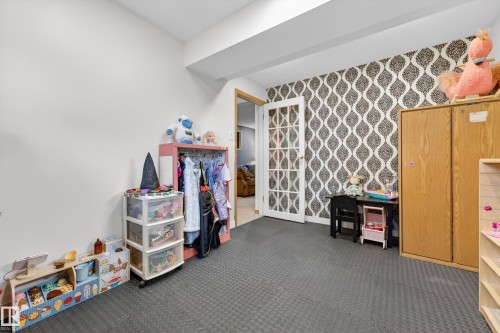 Flexible-use room featuring a patterned accent wall, white French doors, and durable interlocking foam tile flooring - 5304 90A Avenue, Edmonton, AB 