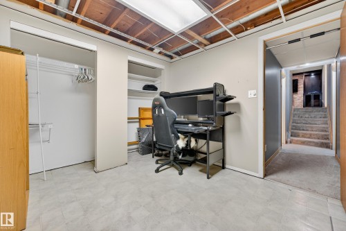 Room featuring light-toned flooring, exposed ceiling joists, and a built-in closet with shelving - 5304 90A Avenue, Edmonton, AB 