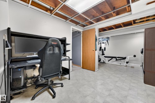Spacious room featuring light gray walls, gray patterned flooring, and exposed ceiling joists - 5304 90A Avenue, Edmonton, AB 