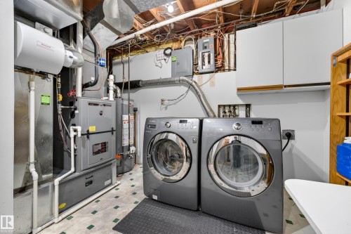 Dedicated laundry area featuring front-loading machines, built-in cabinetry, and utility connections - 5304 90A Avenue, Edmonton, AB 