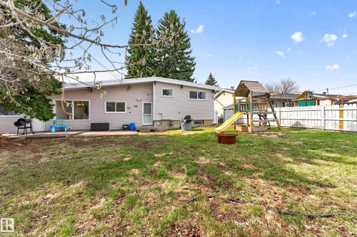 Expansive rear yard with a perimeter fence, mature trees, and a concrete patio at the rear of the residence - 5304 90A Avenue, Edmonton, AB 