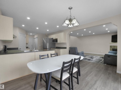Open-concept kitchen and living area featuring wood-finish flooring, recessed lighting, and a fireplace with tile surround - 7407 Singer Landing Landing, Edmonton, AB - Indoor