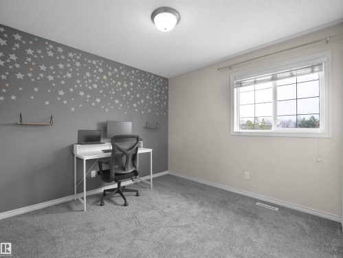Carpeted room featuring a window with grid inserts, light-toned walls, and a gray accent wall - 7407 Singer Landing Landing, Edmonton, AB - Indoor Photo Showing Office