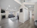 Spacious living area featuring wood-finish flooring, a tiled fireplace with mantel, recessed lighting, and a second-story open railing - 7407 Singer Landing Landing, Edmonton, AB  - Indoor Photo Showing Other Room With Fireplace 