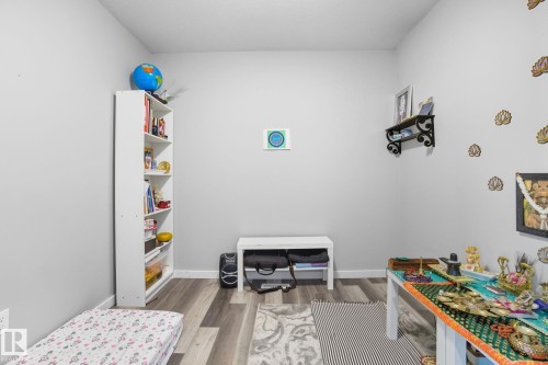 Interior room featuring light gray walls, wood-finish flooring, white baseboards, and a white ceiling - 2039 Wonnacott Way, Edmonton, AB 