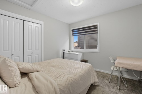 Carpeted bedroom with neutral wall tones and a window featuring horizontal blinds - 2039 Wonnacott Way, Edmonton, AB 