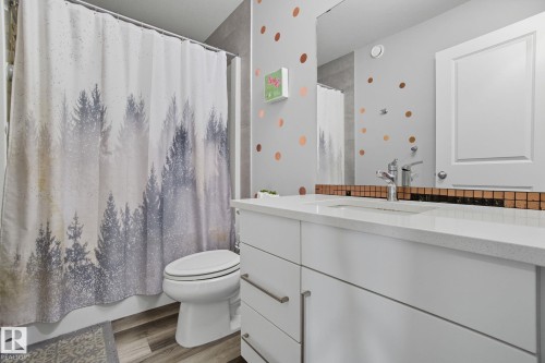 Bathroom featuring a white vanity with an integrated sink, polished chrome faucet, and bronze tile backsplash - 2039 Wonnacott Way, Edmonton, AB 