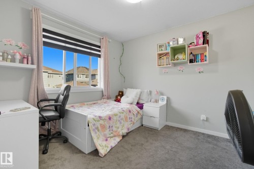 Room featuring a large window with horizontal blinds and drapery, neutral wall paint, and gray carpet flooring - 2039 Wonnacott Way, Edmonton, AB 