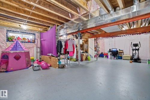 Expansive unfinished basement featuring painted concrete flooring, exposed ceiling joists, and visible ductwork - 2039 Wonnacott Way, Edmonton, AB 