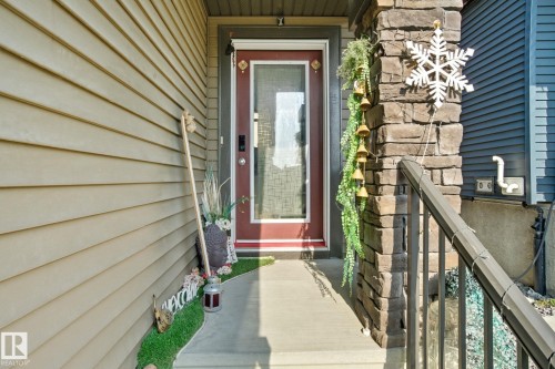 Entryway featuring a red glass-panel door, stone-clad pillar, and an exterior railing - 2039 Wonnacott Way, Edmonton, AB 