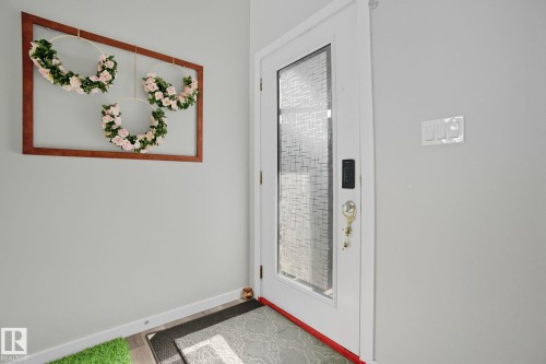 Entry door with frosted privacy glass panel, white trim, and a smart lock system - 2039 Wonnacott Way, Edmonton, AB 