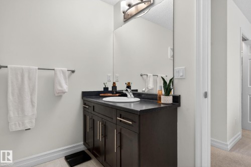 Bathroom with a dark wood vanity, a white vessel sink, and a large mirror - 1014 162 St Sw, Edmonton, AB - Indoor Photo Showing Bathroom