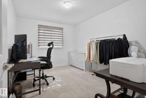 This room features light-colored carpeting, white walls, and a window with horizontal blinds - 1014 162 St Sw, Edmonton, AB - Indoor Photo Showing Office